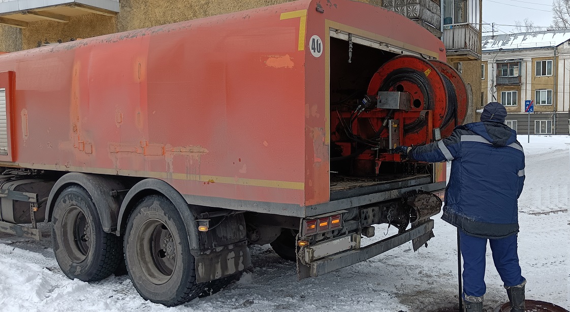 Каналопромывочная машина и работник прочищают засор в канализационной системе в Рыбинске